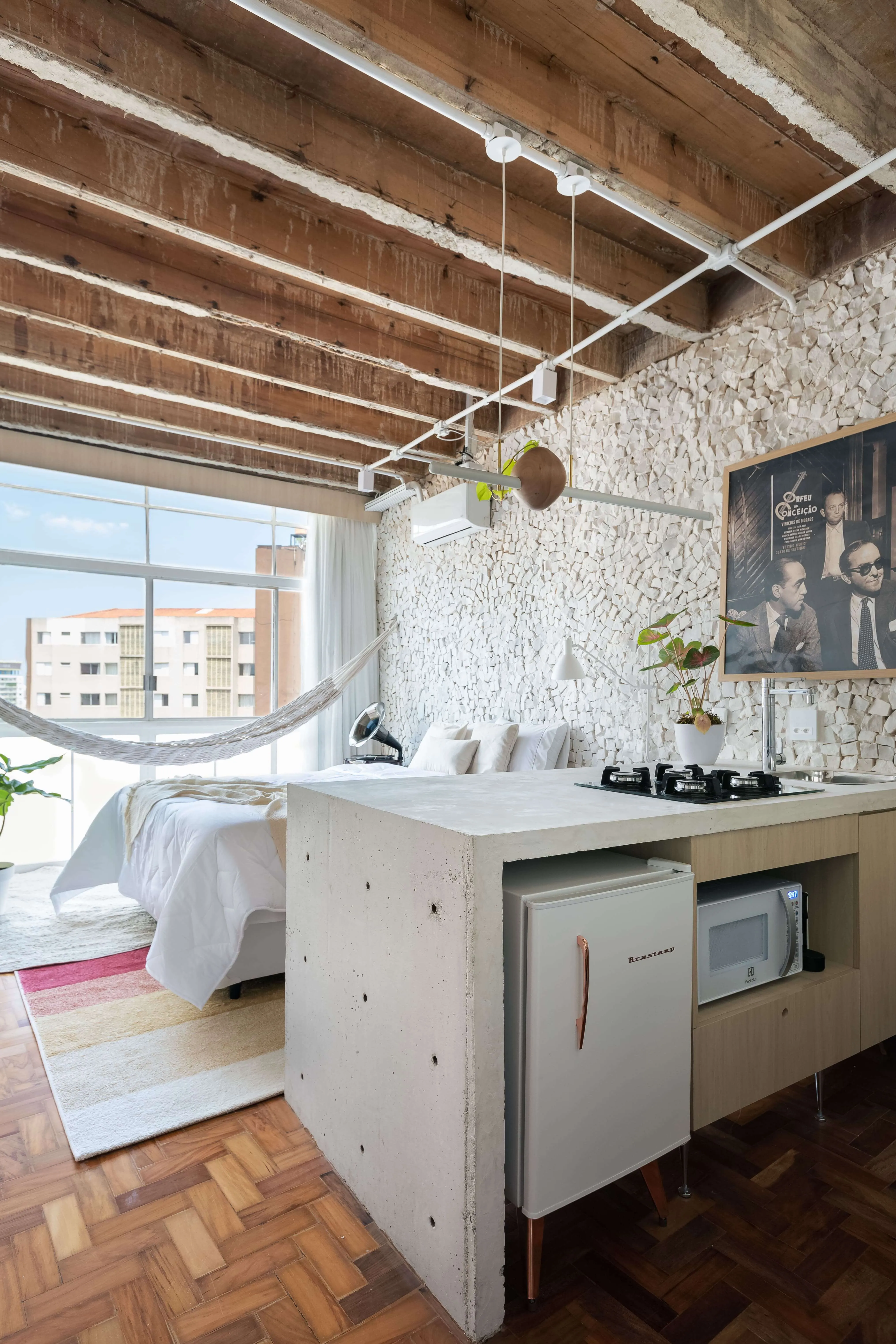 Detalhes da ilha da cozinha, vista do teto, piso, janela e cama integrados ao ambiente.