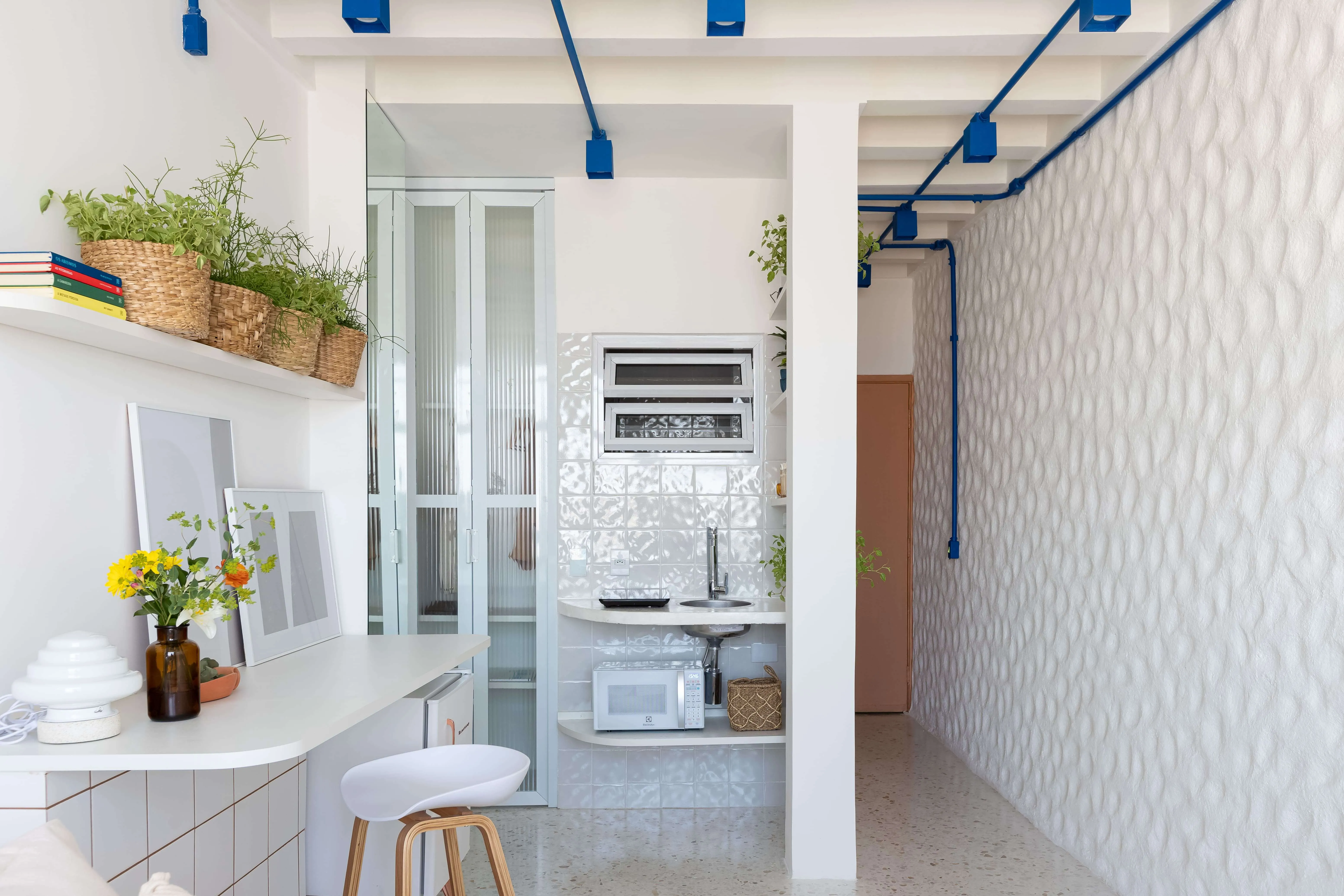 Área da cozinha e corredor de entrada iluminado.